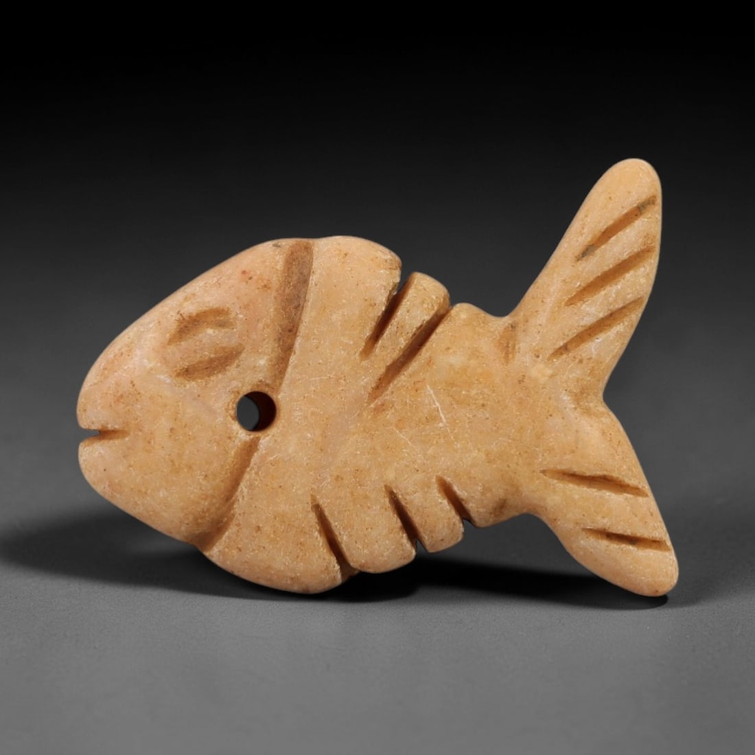 Ancient Egyptian Stone Fish Amulet - Geometric Scale Carving, 56AE: Carved from stone, this ancient Egyptian fish amulet features a stylized piscine form with geometrically incised scale details, typical of protective amulets from the Late Period (c. 664-332 BCE). The