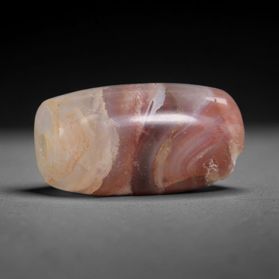 Ancient Banded Agate Bead - Near Eastern Artifact, 9BD: This artifact is crafted from natural banded agate, shaped into an elongated barrel form with striking concentric banding in warm red, cream, and amber hues. The bead features a central perforation fo