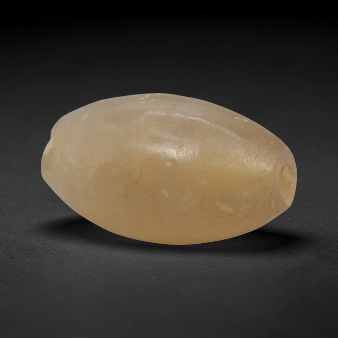 Ancient Agate Bead - Indus Valley Barrel Bead, 63XW: This bead is carved from translucent honey-yellow chalcedony agate, shaped into a smooth, elongated barrel form with a precisely centered axial drill hole, characteristic of Indus Valley (Harappan) la