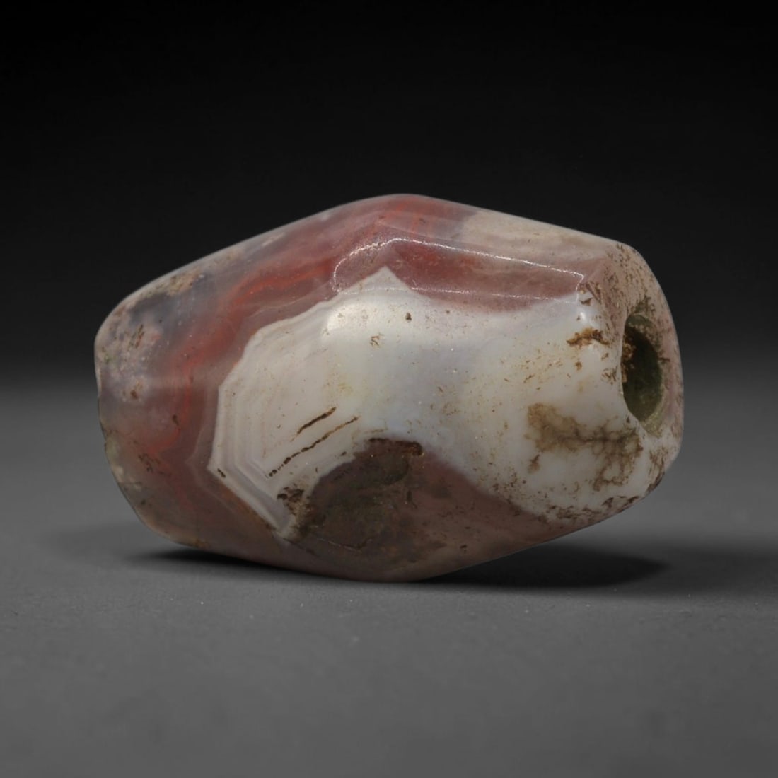 Ancient Agate Bead - Bactrian Faceted Banded Carnelian Bead, 58XW: This bead is carved from translucent deep red carnelian and creamy-white banded agate, shaped into a robust, faceted barrel form with a precisely centered axial drill hole, characteristic of ancient B