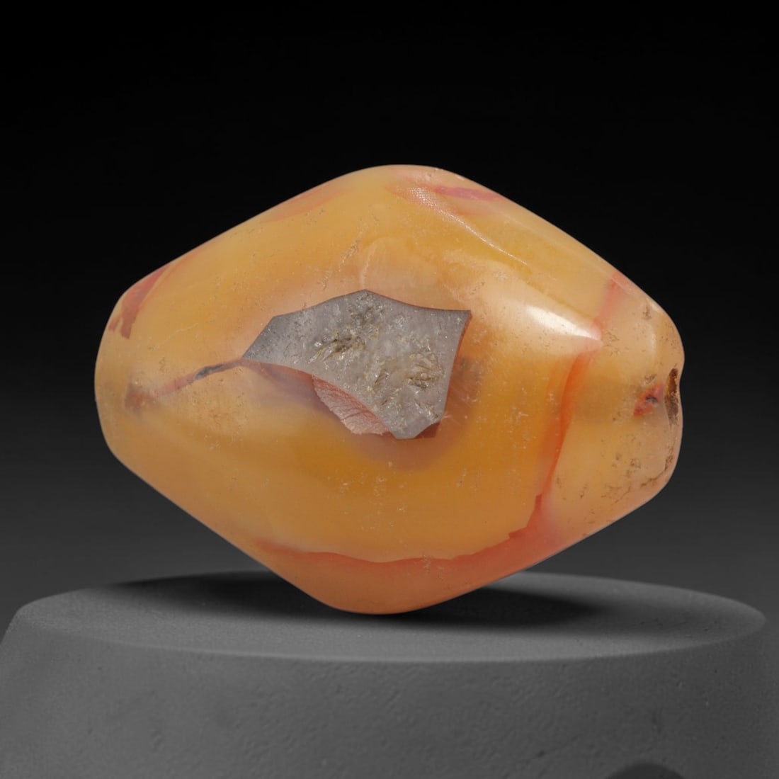 Ancient Agate Bead - Bactrian Faceted Bicone Bead, 12XW: This bead is carved from translucent honey-amber banded agate with striking coral-red mineral striations, shaped into a refined bicone (expanded barrel) form with a precisely centered axial drill hole