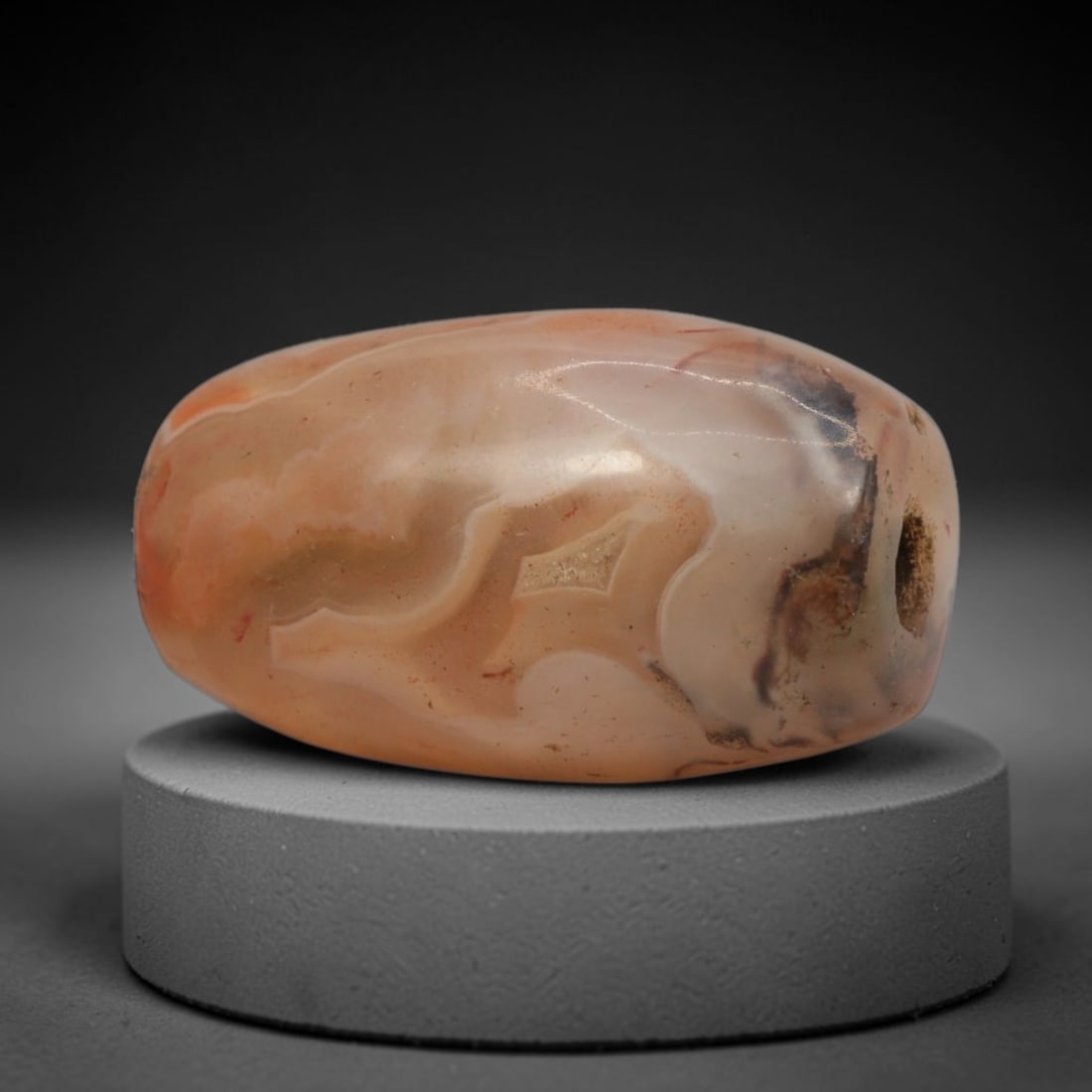 Ancient Agate Bead - Bactrian Banded Barrel Bead, 4XW: This bead is carved from translucent peach-pink banded agate, shaped into a smooth, compact barrel form with a precisely centered axial drill hole, characteristic of ancient Bactrian lapidary craftsma