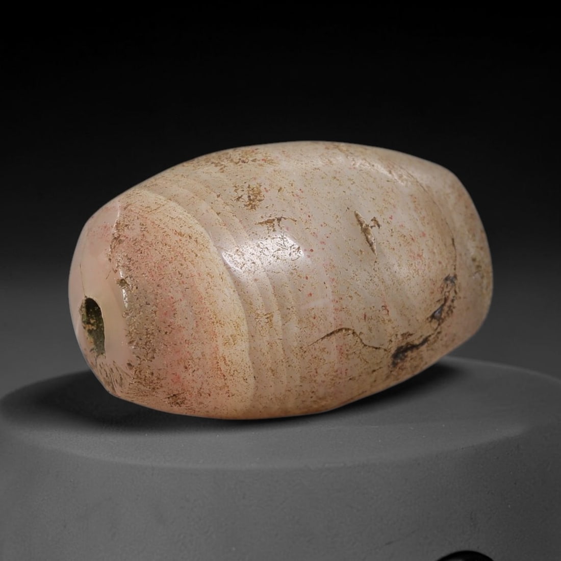 Ancient Agate Bead - Indus Valley Artifact, 18BD: This artifact is crafted from banded agate, exhibiting a smooth, ovoid form with natural banded patination indicative of ancient geological formation and long-term burial. The bead features a central