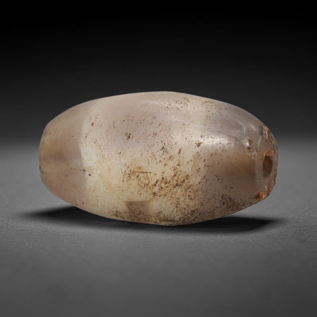 Ancient Agate Bead - Bactrian Banded Bicone Bead, 16XW: This bead is carved from translucent milky-grey and creamy-white banded agate, shaped into a smooth, compact bicone (elongated almond) form with a precisely centered axial drill hole, characteristic o