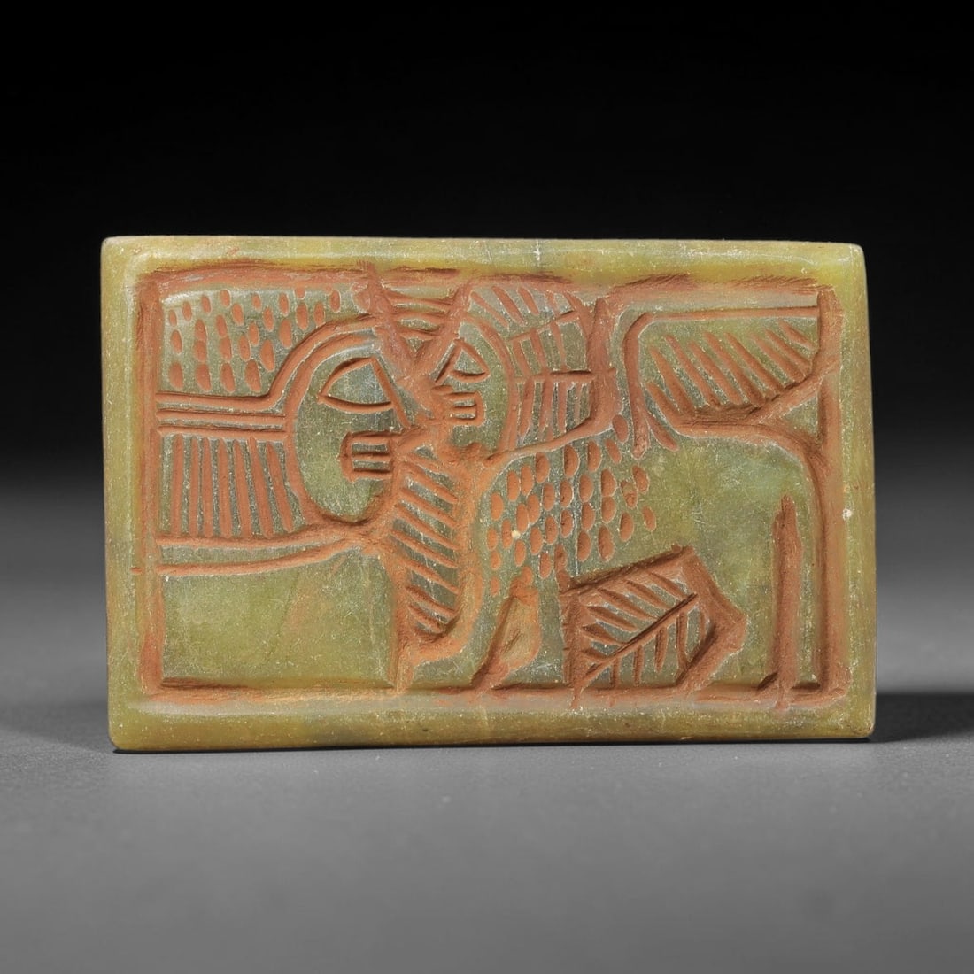 Near Eastern Serpentine Plaque - Tribal Art Figure & Animal Relief, 52BF: Carved from serpentine, this rectangular plaque features a deeply incised relief composition with a stylized human face, a humanoid figure, and a winged zoomorphic form, rendered in a bold, linear tri