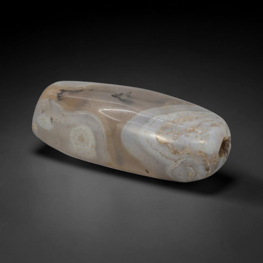 Ancient Agate Bead - Bactrian Dendritic Banded Bead, 34XW: This bead is carved from translucent milky-grey banded agate, shaped into a smooth, elongated barrel form with a precisely centered axial drill hole, characteristic of ancient Bactrian lapidary crafts