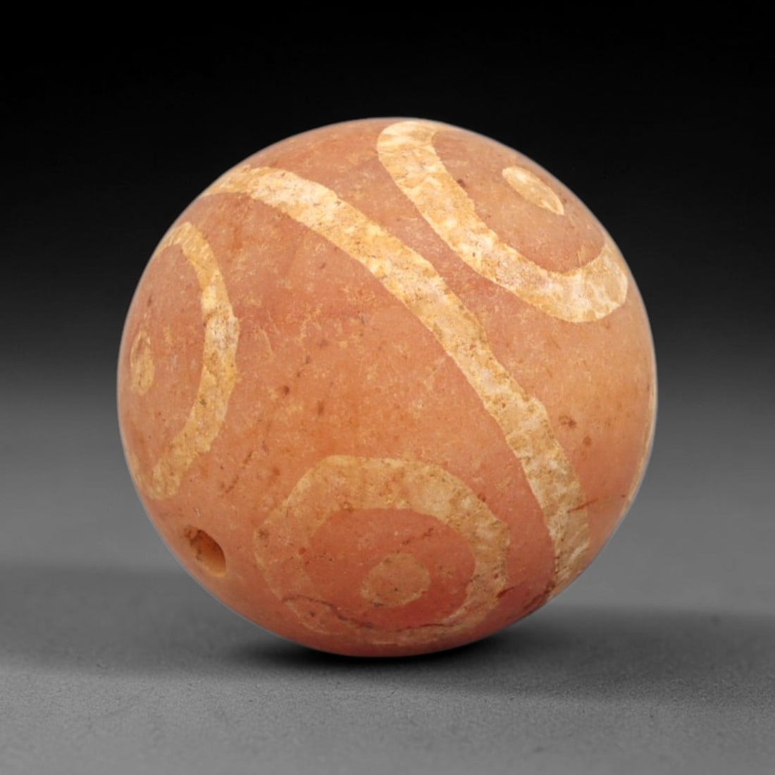 Ancient Carnelian Etched Bead - Gandhara Spherical Bead, 41XY: The bead is fashioned from carnelian, a semi-precious chalcedony, with a perfectly spherical form and a laterally drilled suspension hole for wear. Its surface is decorated with a traditional etched w