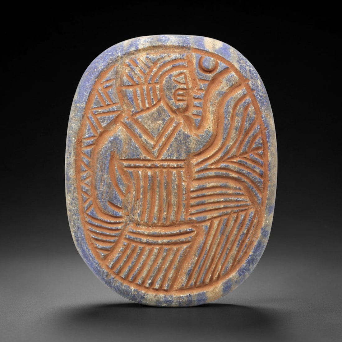 Near Eastern Lapis Lazuli Plaque - Tribal Art Figure Relief, 91ZY: Carved from natural lapis lazuli stone, this Near Eastern tribal art plaque relief features a hand-carved oval form depicting a stylized human figure, executed with incised linear and geometric techni