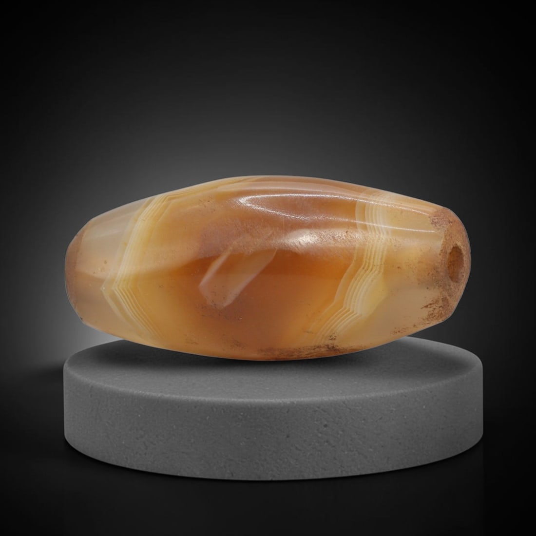 Ancient Agate Bead - Indus Valley Banded Carving, 77WJ: This artifact is crafted from banded agate, exhibiting striking concentric banding in warm amber and creamy white tones across its polished, faceted surface. The bead is shaped in an elongated, bicone