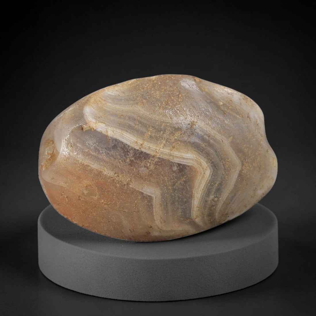 Ancient Agate Bead - Silk Road Natural Form Amulet, 99BD: Carved from banded agate, the bead features a smooth, naturally shaped oval form with a polished surface that highlights the stone's striking "chevron" (V-shaped) concentric banding, ranging from crea