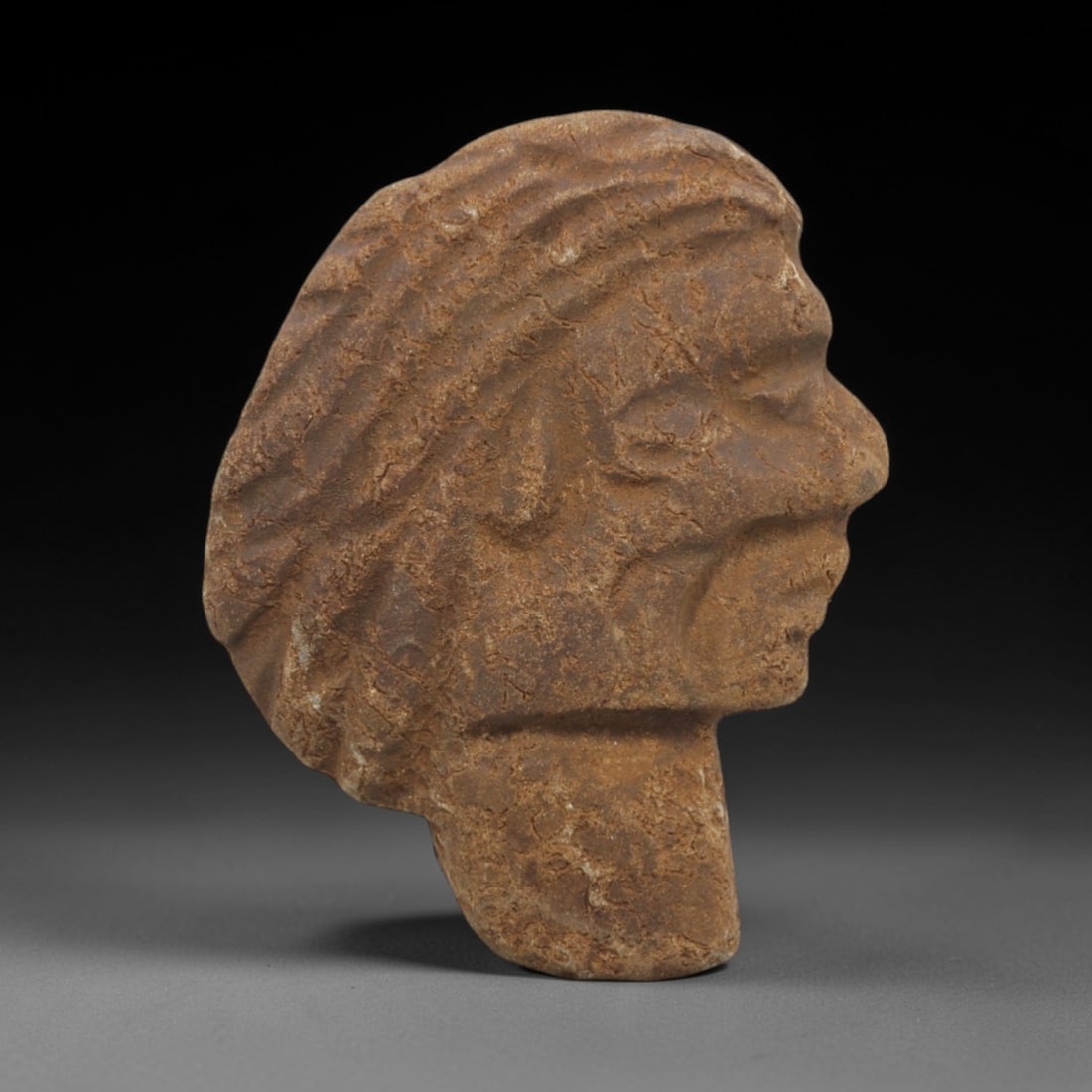 Ancient Stone Near Eastern Head - Proto-Figurine, 8FX: Carved from a dense, earthen-brown stone with a heavily textured, weathered surface, this artifact presents a refined Near Eastern anthropomorphic head in profile, characterized by a pronounced nasal