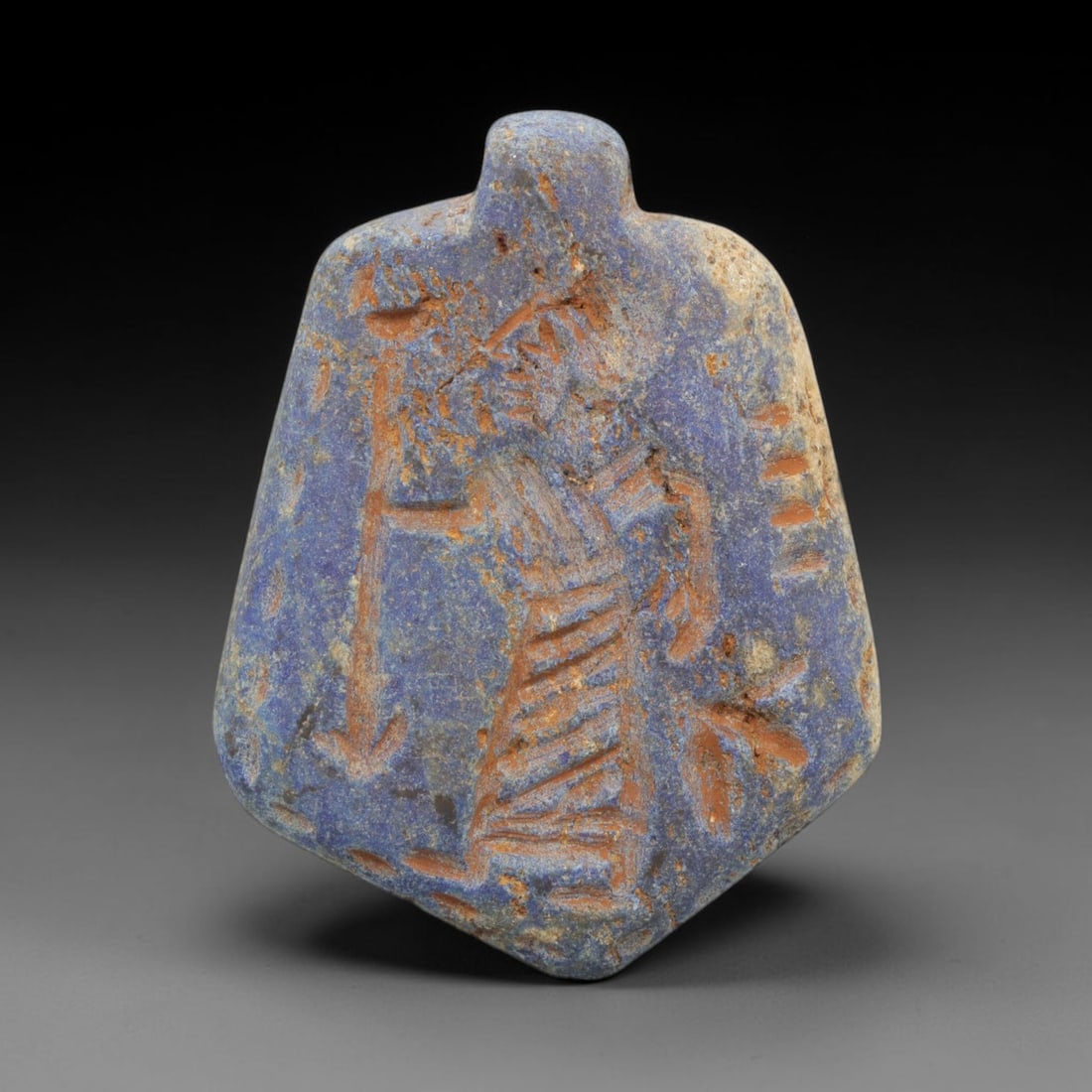 Ancient Lapis Lazuli Amulet - Near Eastern Human Figure, 100ZT: Carved from lapis lazuli, this amulet features a relief depiction of a standing human figure, rendered in the stylized glyptic tradition of the ancient Near East. The figure is detailed with incised l
