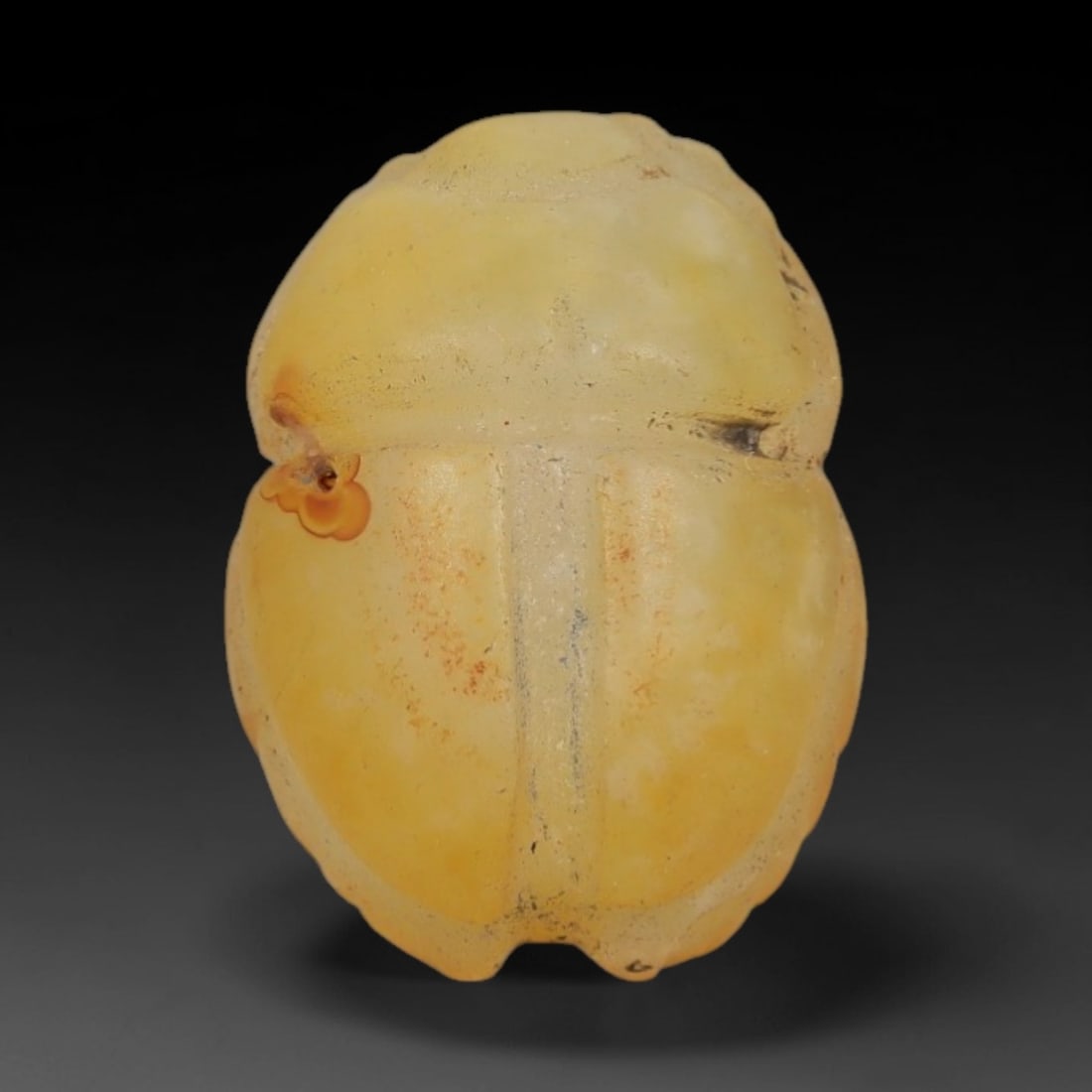 Ancient Chalcedony Scarab Amulet - Egyptian Figurine, 54AJ: Carved from smooth, warm yellow chalcedony with natural orange-brown inclusions and subtle surface markings, this amulet is formed as a stylized scarab beetle with incised linear detailing to define t