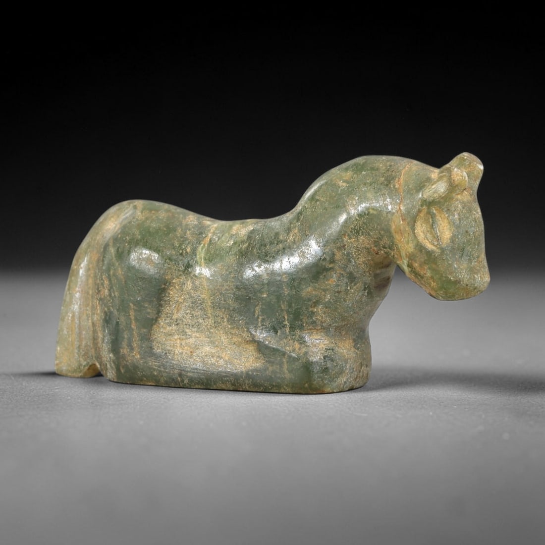 Ancient Serpentine Horse - Near Eastern Amulet Figurine, 45AS: Carved from serpentine, this amulet depicts a recumbent horse with simplified, stylized features. The head is lowered, with incised eye sockets, small rounded ears, and a smooth muzzle, while the body