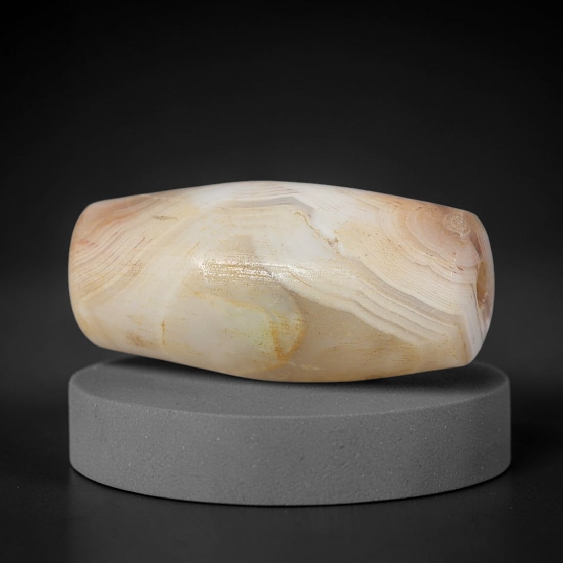 Ancient Agate Bead - Silk Road Miniature Amulet, 2BD: Carved from banded agate, the bead features a short cylindrical barrel form with a smooth, polished surface that highlights the stone's natural concentric banding, ranging from creamy white to warm ho