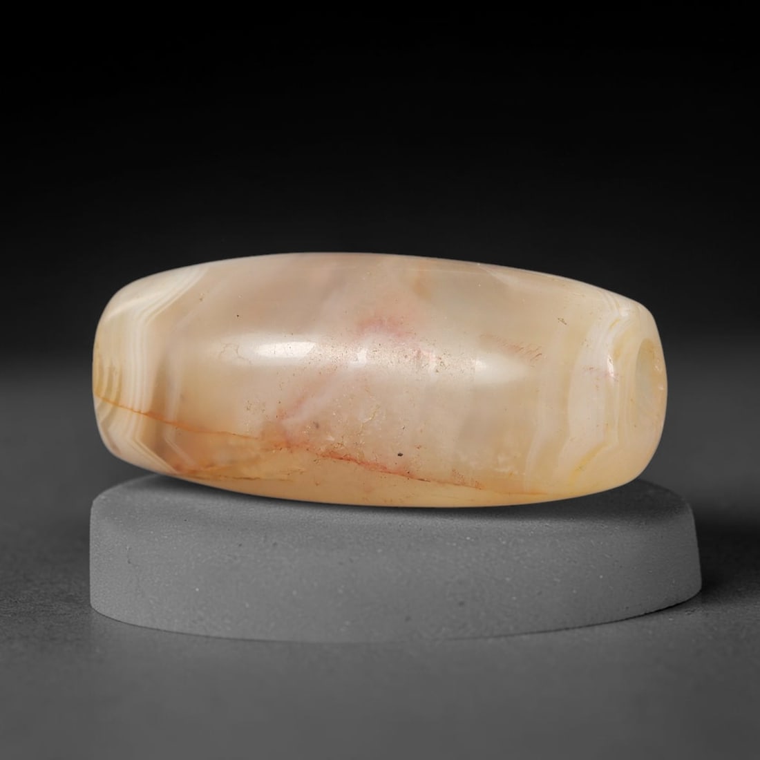 Ancient Agate Bead - Indus Valley Amulet, 21BD: This artifact is crafted from translucent honey-toned agate, exhibiting subtle wavy banding and faint red mineral inclusions across its smooth elongated barrel form, shaped through skilled ancient lap