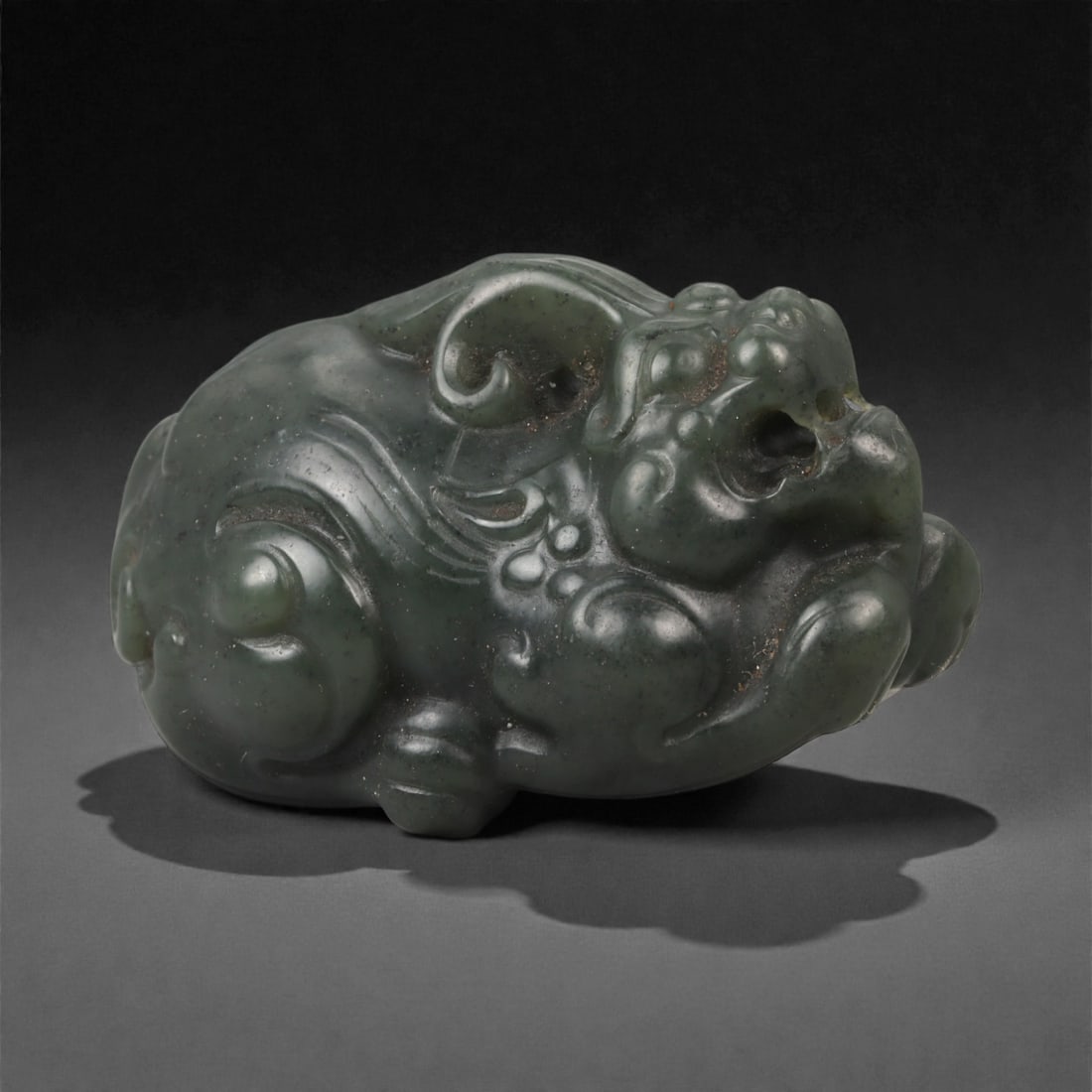 Chinese Jade Pixiu Beast - Carved Stone Figurine, 89ZD: Carved from dark green jade with subtle tonal mottling, this compact sculpture represents a crouching pixiu modeled in the round, with pronounced haunches, curling mane details, and a stylized head re