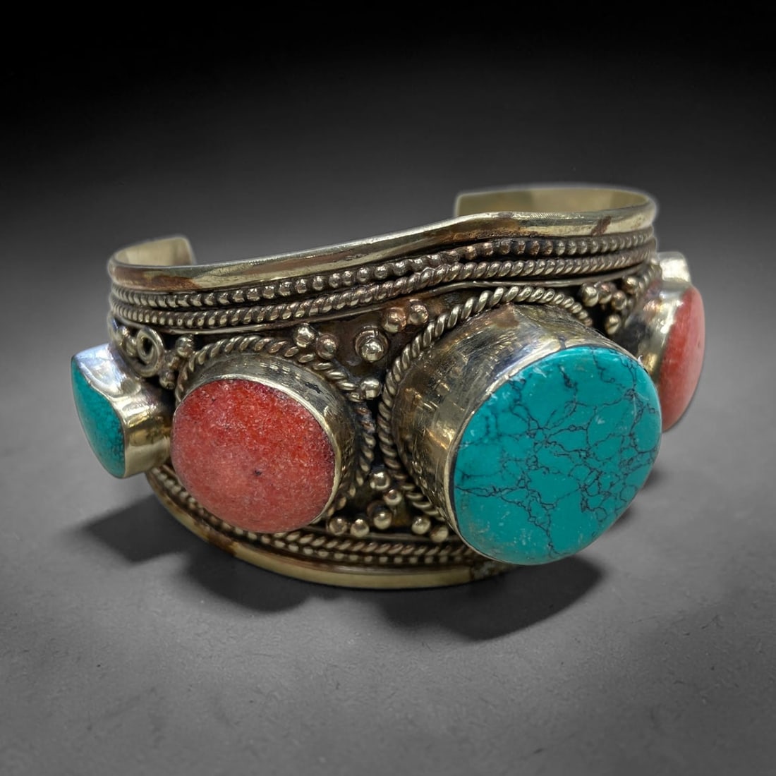 Old Himalayan Turquoise Coral Cuff - Metalwork Ornament, 137g, 66AA: This open-cuff bracelet features a bold arrangement of large, raised stone cabochons, including a prominent round turquoise with natural matrix veining, round coral, and smaller accent stones, all bez