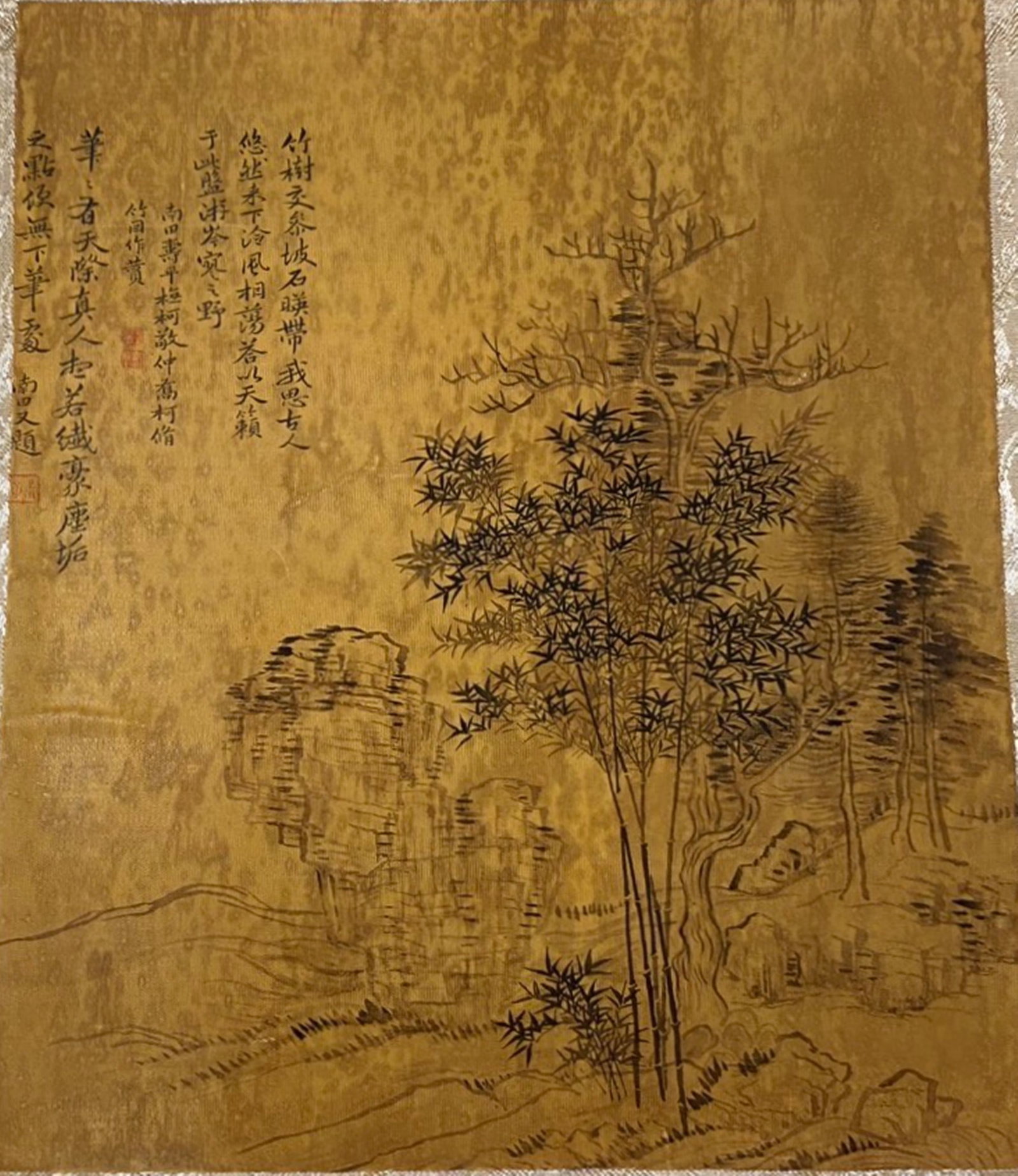 A Chinese Ink and Color Textile Print, Bamboo and Rock, 20th Century, 27FK: Printed on woven silk or hemp textile with a gold-toned ground, the composition depicts a classic literati scene of bamboo groves growing beside a rugged rock formation, with sparse trees and distant