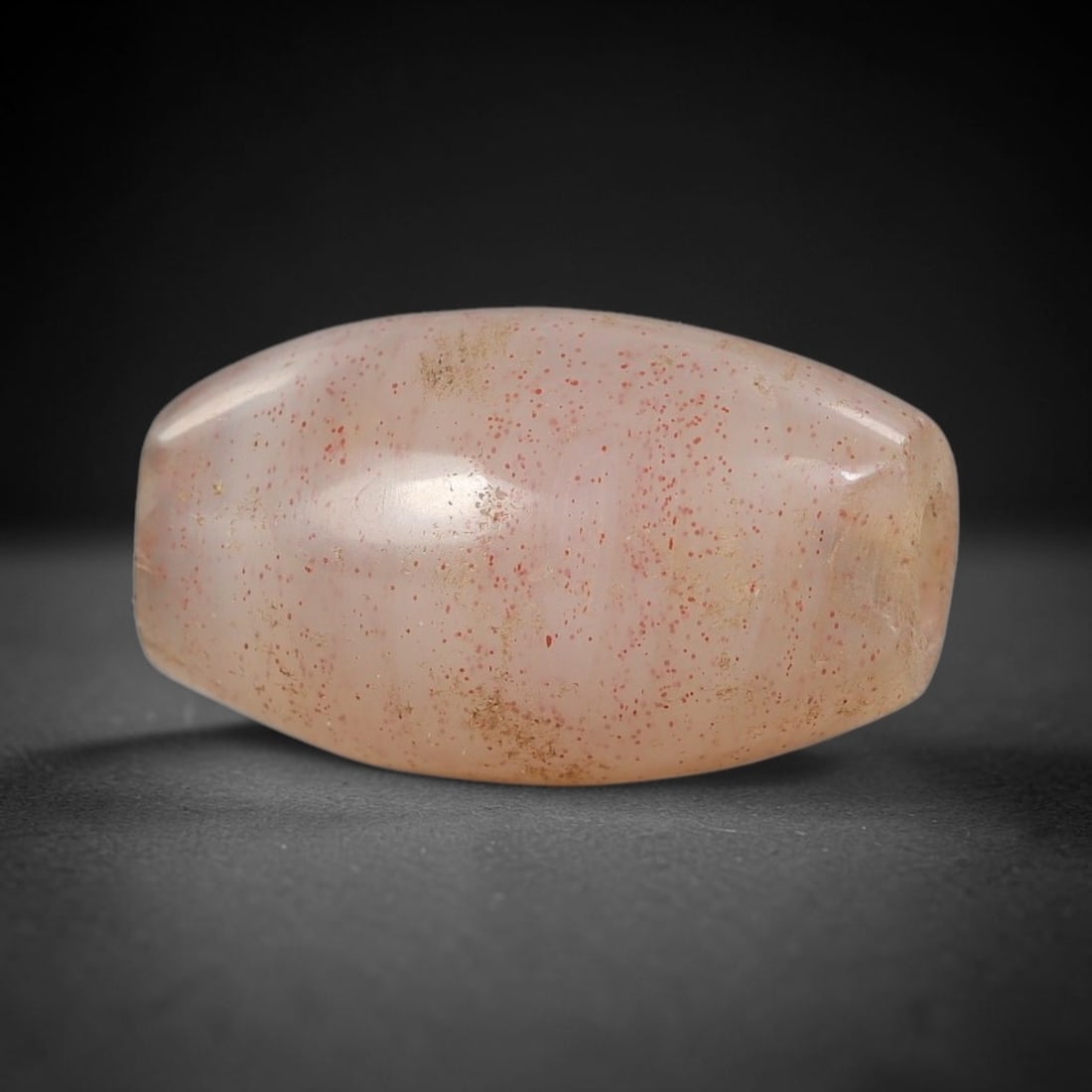 Ancient Agate Bead - Silk Road Miniature Bicone Amulet, 76BD: Carved from translucent agate, the bead features a smooth bicone (double-pointed) form with a polished surface that highlights the stone's pale milky-pink base, densely speckled with fine red mineral
