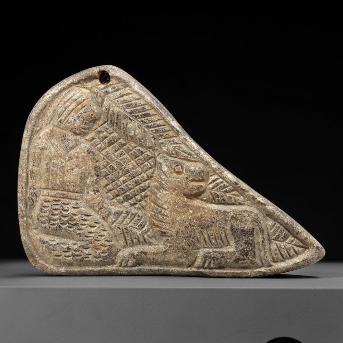 Ancient Stone Plaque Relief - Near Eastern Human & Equine Figurine, 68BE: Carved from a single piece of stone, this triangular relief plaque features a seated human figure beside a standing equine, rendered in the stylized, linear artistic tradition of the ancient Near East