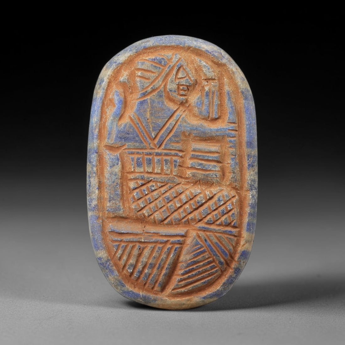 Near Eastern Lapis Lazuli Plaque - Tribal Art Figure Relief, 74BF: Carved from lapis lazuli, this oval plaque features a relief depiction of a stylized human figure, executed in the linear, geometric style characteristic of Near Eastern tribal art. The figure is rend