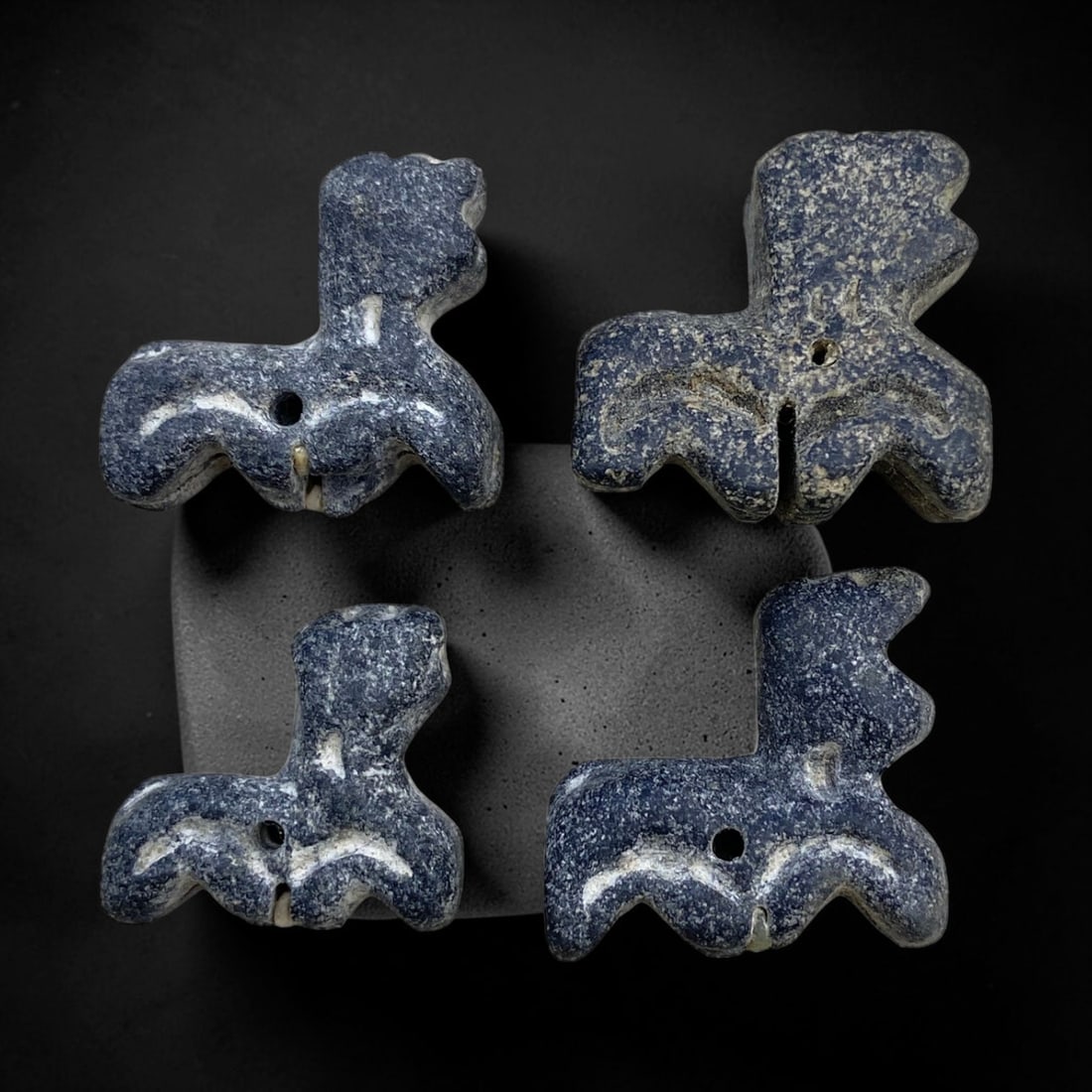 Ancient Bactrian Stone Zoomorphic Feline Amulets - Set of 4, 25g, 81AA: This collection comprises four ancient zoomorphic amulets, each carved from a dense, dark grey/black stone with a naturally weathered surface showing subtle earthen deposits and fine textural patina, 
