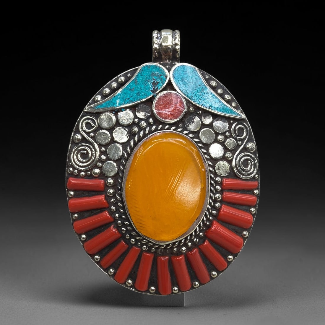 Old Himalayan Amber Inlay Pendant - Metalwork Ornament, 57g, 69AA: This oval pendant features a large central oval amber cabochon, bezel-set within an ornate metal frame. The frame is adorned with traditional Himalayan metalworking techniques, including twisted wire