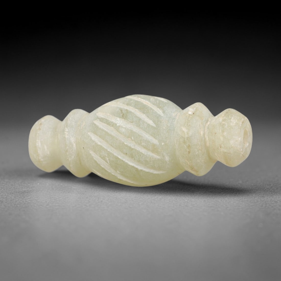 Ancient Serpentine Bead Amulet - Near Eastern Pendant, 36AR: This artifact is carved from pale, translucent green serpentine, exhibiting a smooth, polished surface with subtle natural inclusions and faint surface wear consistent with age. The form is an elongat