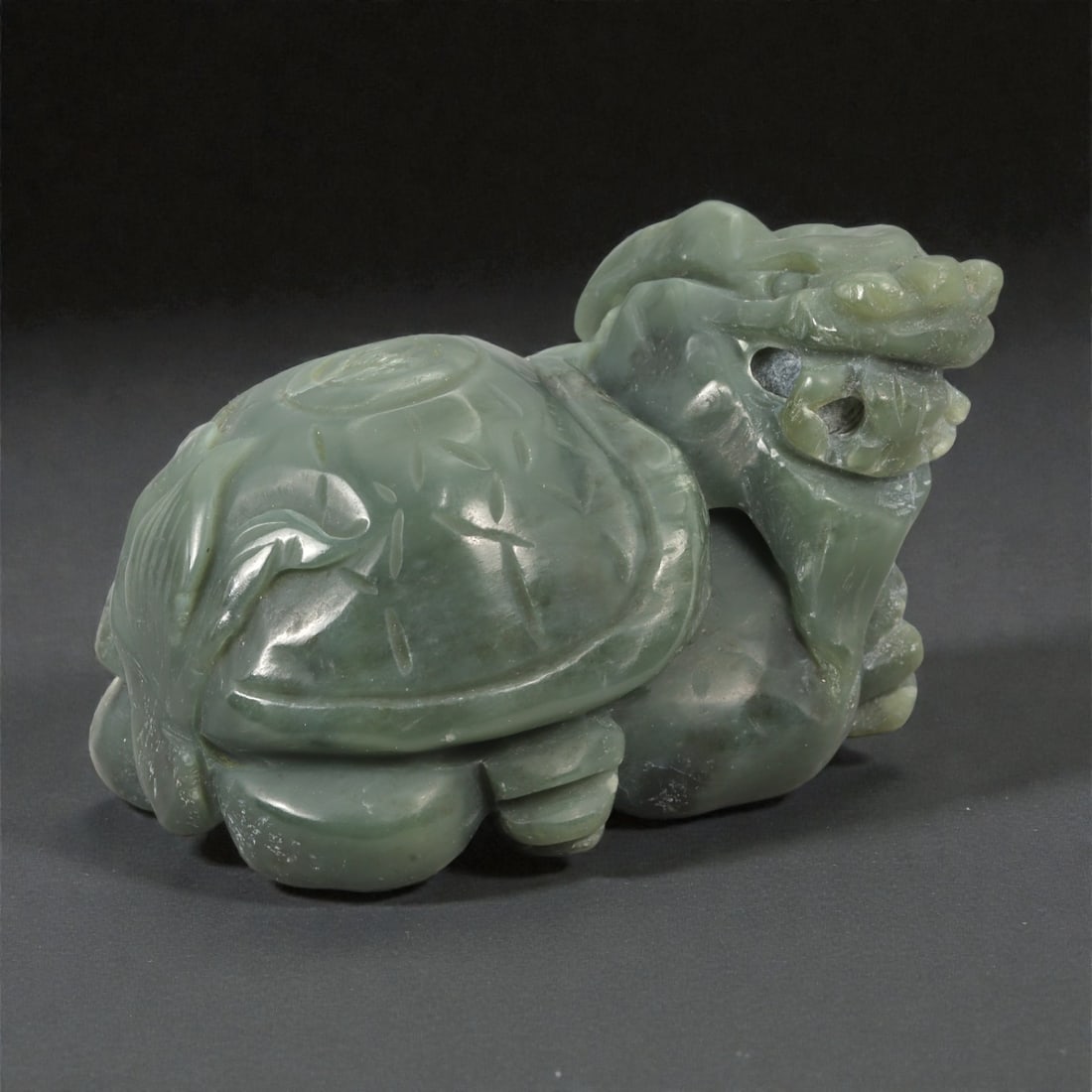 A Chinese Jade Dragon Turtle (Bixi) Sculpture, 20th Century, 88YA: Carved from green jade with areas of darker and lighter tonal variation and natural translucency, the sculpture represents a dragon turtle (bixi) modeled fully in the round. The creature is shown in a