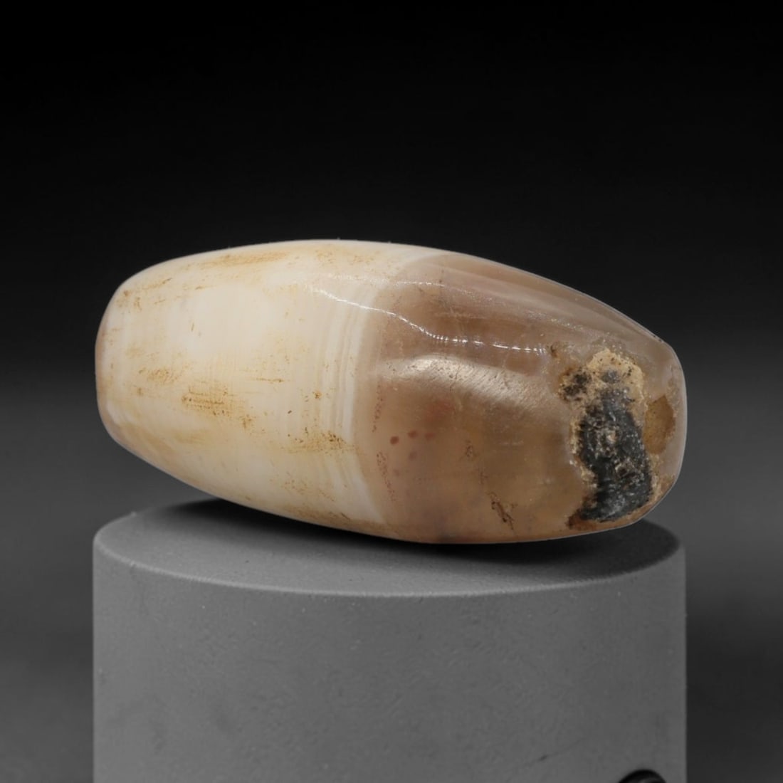 Ancient Agate Bead - Western Asiatic Barrel Bead, 31XW: This bead is fashioned from banded agate with distinct layers of creamy-white and warm taupe-brown mineralization, shaped into a smooth, elongated barrel form with a centrally drilled axial suspension