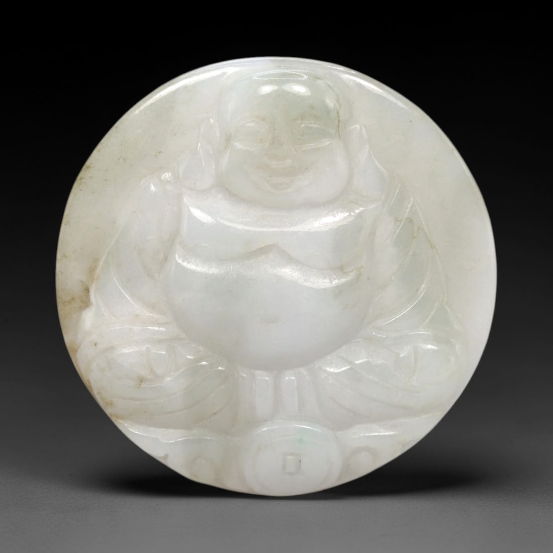 A Chinese Jadeite Jade Budai Pendant, 20th Century, 94FR: Carved from pale translucent jadeite jade with natural inclusions and subtle tonal variations, the pendant is circular in form. It depicts Budai, the laughing Buddha, seated in a relaxed posture with 