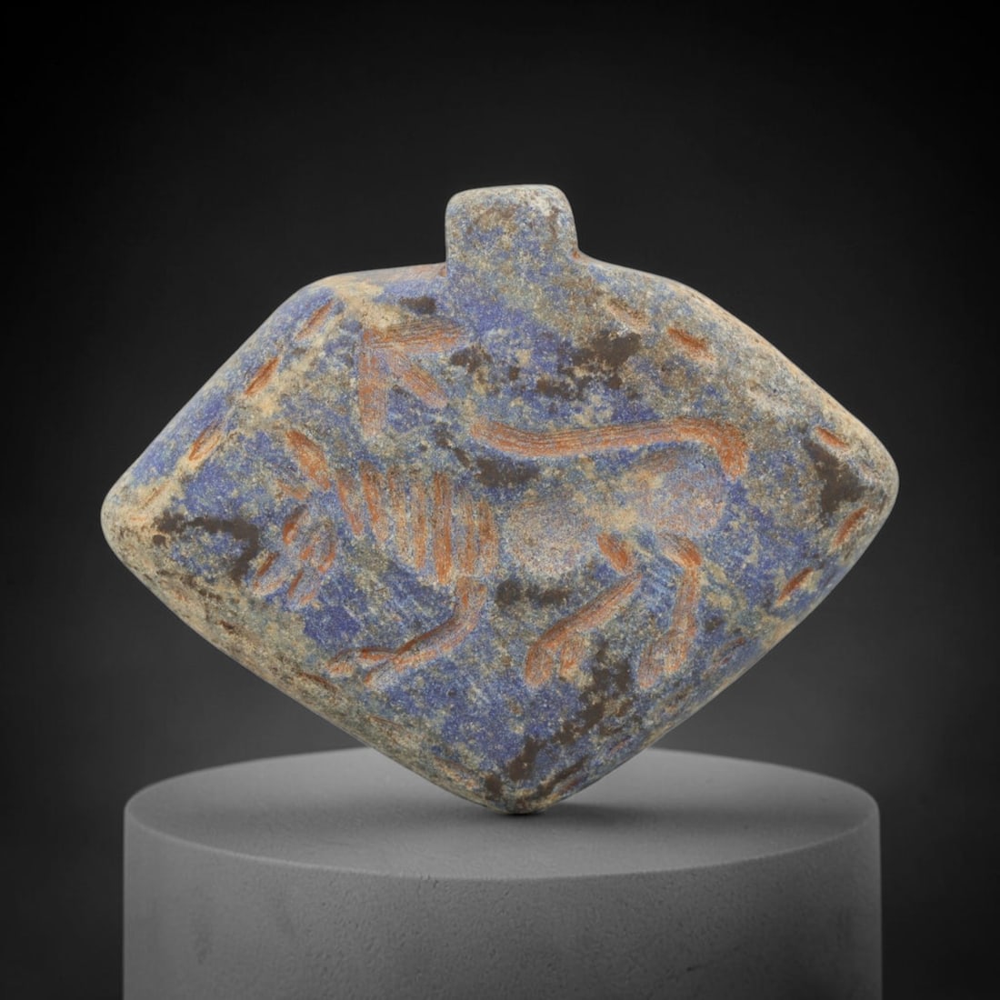 Ancient Lapis Lazuli Amulet - Near Eastern Lion Figure, 4ZX: Carved from lapis lazuli, this amulet features a relief depiction of a striding lion, rendered in the stylized glyptic tradition of the ancient Near East. Incised details define the lion's muscular bo