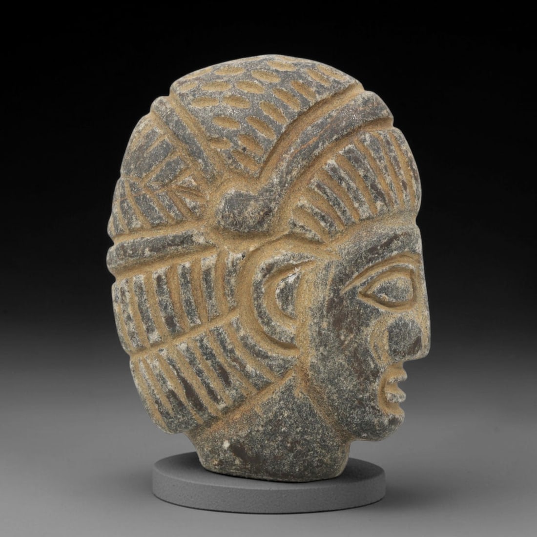 Ancient Stone Head - Near Eastern Anthropomorphic Figurine, 21ZX: Carved from stone, the artifact is a three-dimensional human head in profile, crafted in the ancient Near Eastern style. The surface bears incised details rendering an elaborate, geometric-patterned h
