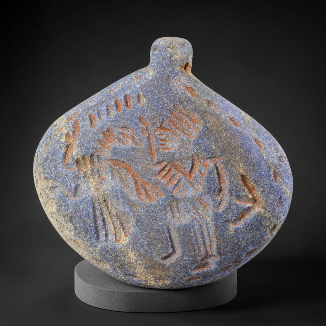 Ancient Lapis Lazuli Amulet - Near Eastern Dual Figure Figurine, 27BA: Carved from lapis lazuli, the amulet takes a rounded, bulbous form with a suspension loop at the top, designed for wear as a protective talisman. The front face is incised with two stylized anthropomo
