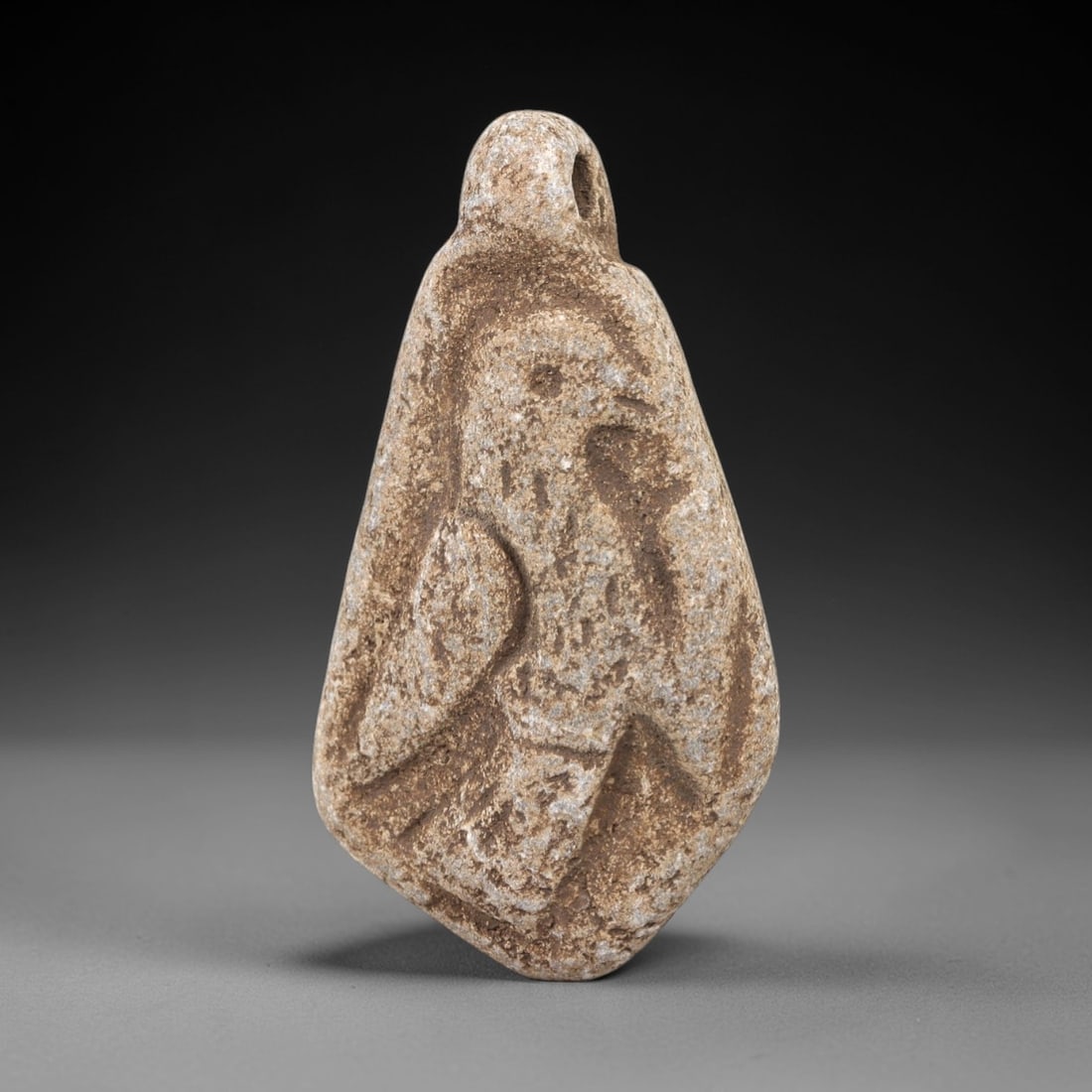 Ancient Stone Bird Amulet - Near Eastern Figurine, 2FX: Carved from weathered stone, this teardrop-shaped amulet features a low-relief depiction of a stylized bird, with incised linear details defining the head, beak, wings, and body, alongside a suspensio