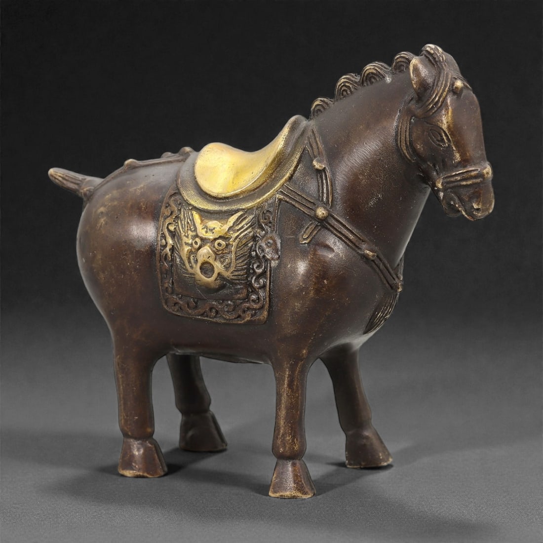 A Chinese Bronze Horse Effigy, 20th Century, 28FH: Cast in bronze as a standing horse, the figure is modeled with a compact body, straight legs terminating in simplified hooves, and a slightly lowered head with stylized facial features and incised man