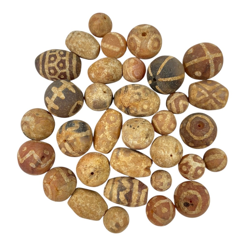 A Lot of 33 Ancient Etched Carnelian Beads, Gandhara Style, 72AA: This collection includes 33 ancient etched carnelian beads, characteristic of Gandhara-period craftsmanship. Crafted from natural carnelian, they display warm reddish-brown and terracotta hues, adorne