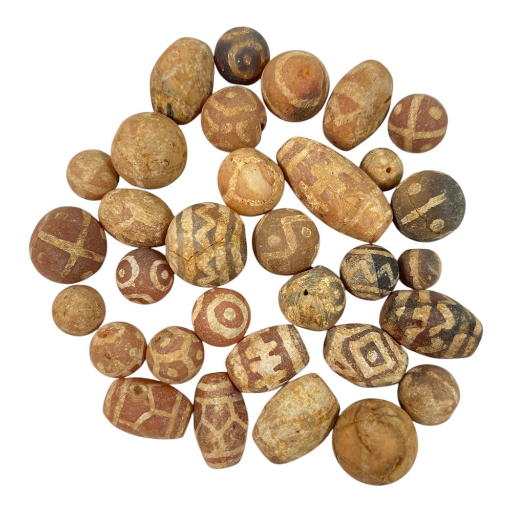 A Lot of 32 Ancient Etched Carnelian Beads, Gandhara Style, 73AA: This collection features 32 ancient etched carnelian beads, characteristic of Gandhara-period craftsmanship. Crafted from natural carnelian, they display warm reddish-brown and terracotta hues, adorne