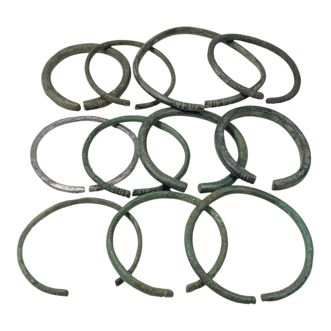 A Lot of 11 Ancient Roman Bronze Bracelets, 33AC: The group comprises 11 open-ended bronze bracelets, exhibiting varying shades of green and brown patina consistent with ancient metalwork, with one example retaining residual silvering. Each bracelet 