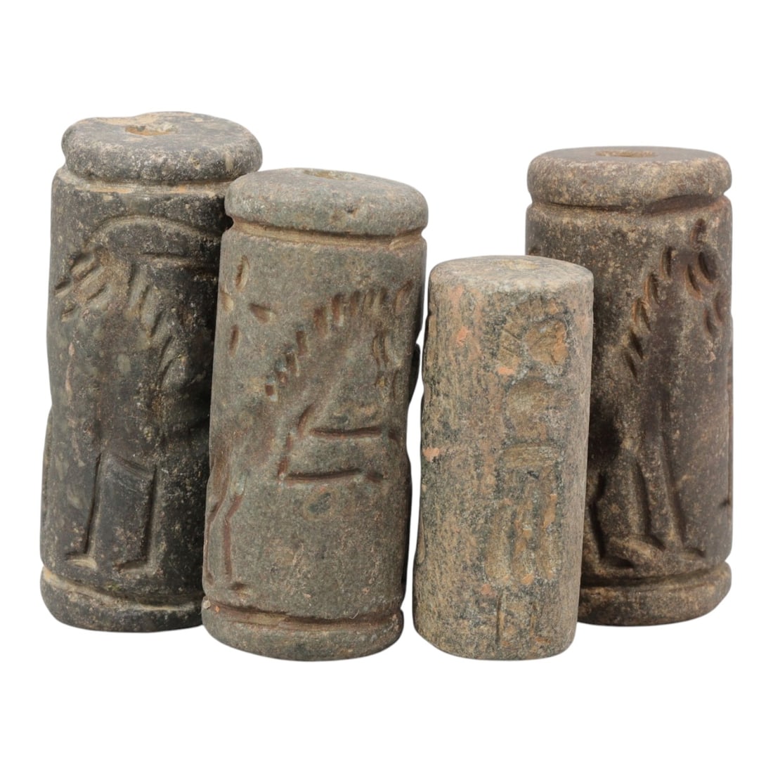 Lot of 4 Ancient Mesopotamian Stone Cylinder Seals, Circa Bronze Age, 10AE: Comprising four dark stone cylinder seals ranging from 3.5 cm to 4.5 cm in height, these pieces are characteristic of the seal-cutting traditions of ancient Mesopotamia. Each seal is carved with deep,