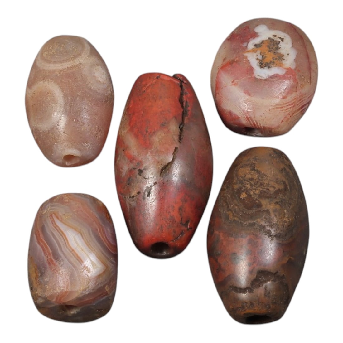 Lot of 5 Ancient to Antique Period Himalayan Silk Road Banded Agate Beads, 57AD: A group of five beads carved from banded agate with varying translucency, dominated by warm red, brown, and pinkish tones, with distinct linear and concentric banding patterns visible throughout. The 