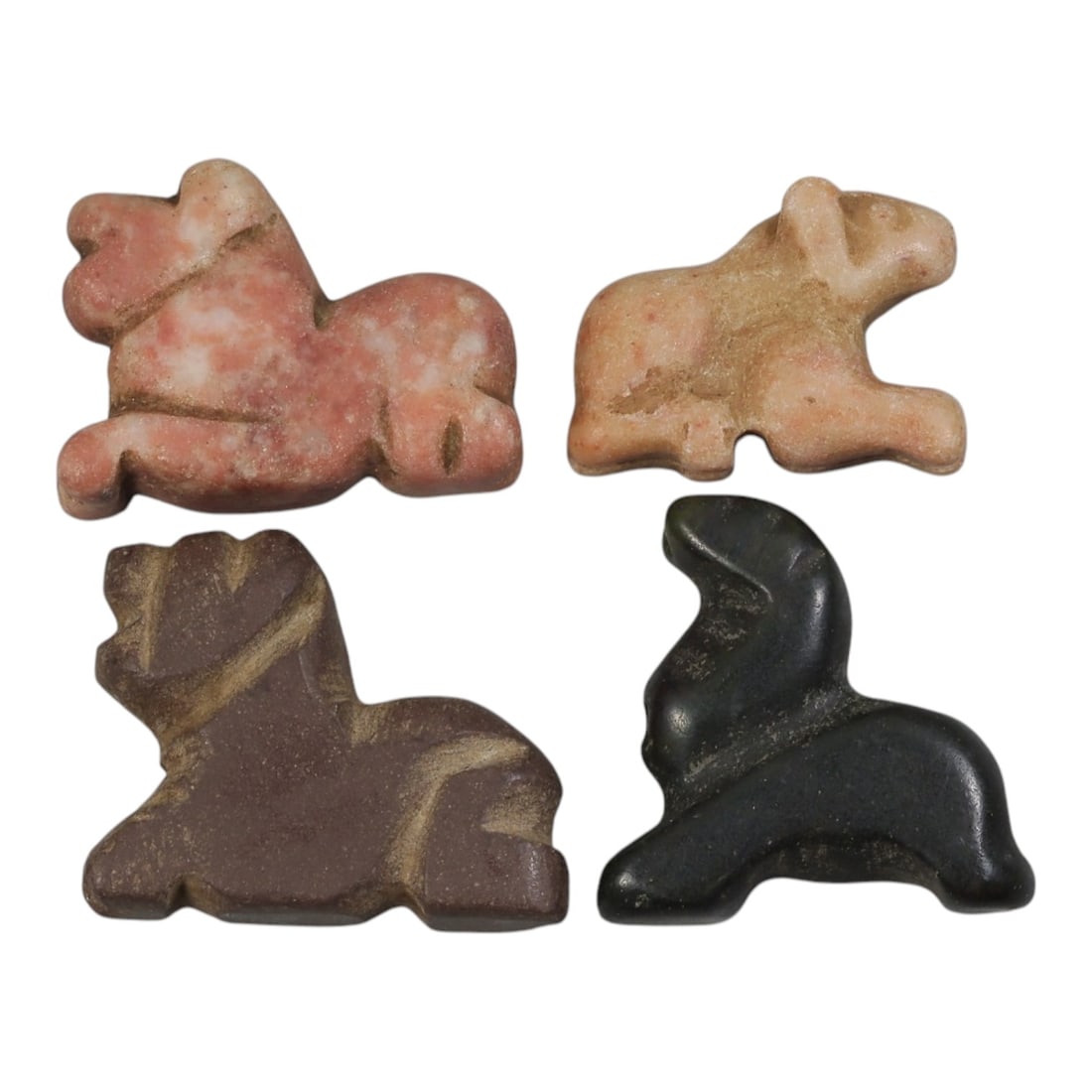 Lot of 4 Ancient Bactrian Zoomorphic Stone Amulets, Circa 3rd-1st Millennium BCE, 79AE: The group comprises four carved zoomorphic amulets depicting recumbent quadrupeds, characteristic of ancient Bactrian art. The pieces are worked in varied stone tones: pink mottled, light pink, reddis