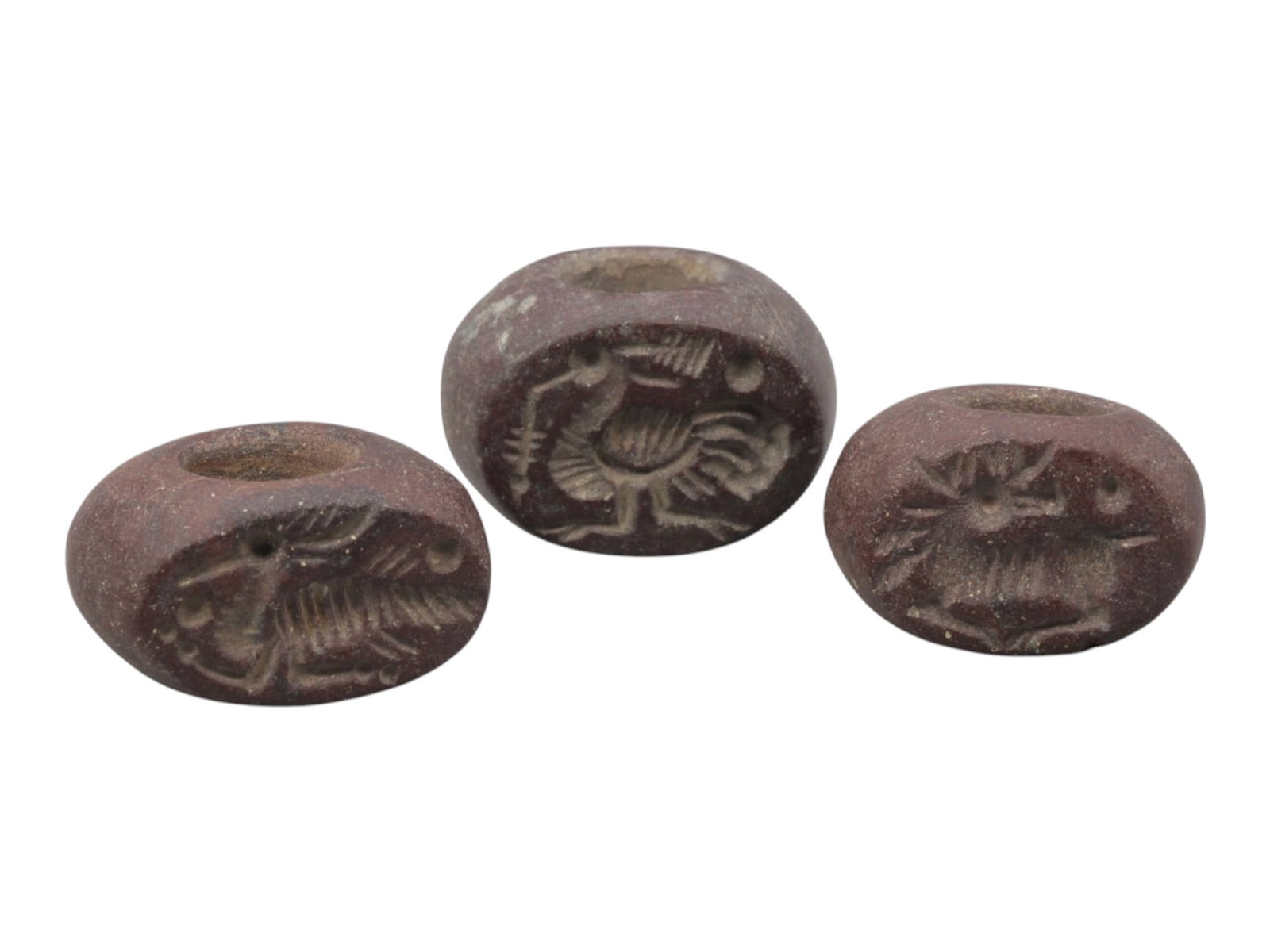 Lot of 3 Sasanian Dark Red Stone Stamp Seals, Circa 3rd-7th Century CE, 64WM: A group of three Sasanian period stamp seals carved from dark red stone, exhibiting natural patination, surface wear, and subtle weathering consistent with age. Each is of rounded, barrel form with a 