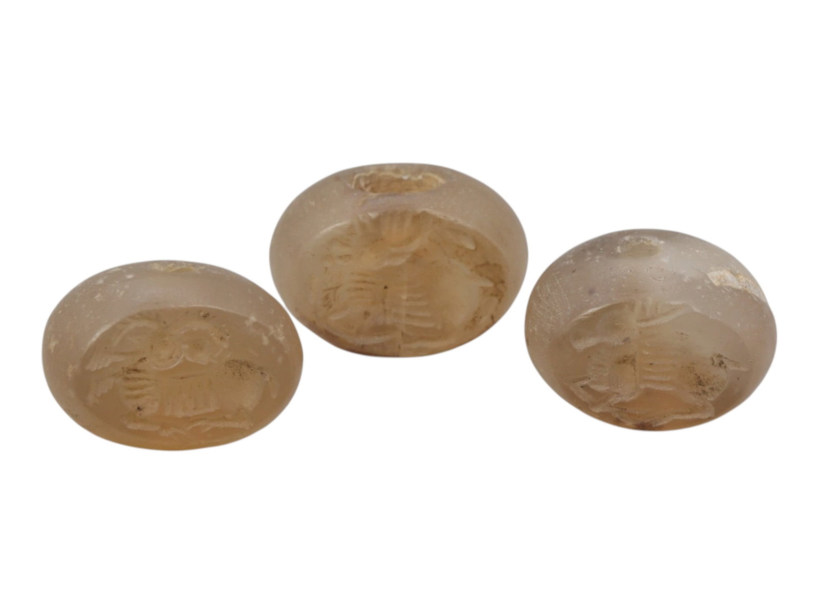 Lot of 3 Sasanian Chalcedony Stamp Seals, Circa 3rd-7th Century CE, 65WM: A group of three Sasanian period stamp seals carved from translucent chalcedony, exhibiting natural pale beige tones with surface patination and minor weathering consistent with age. Each is of rounde