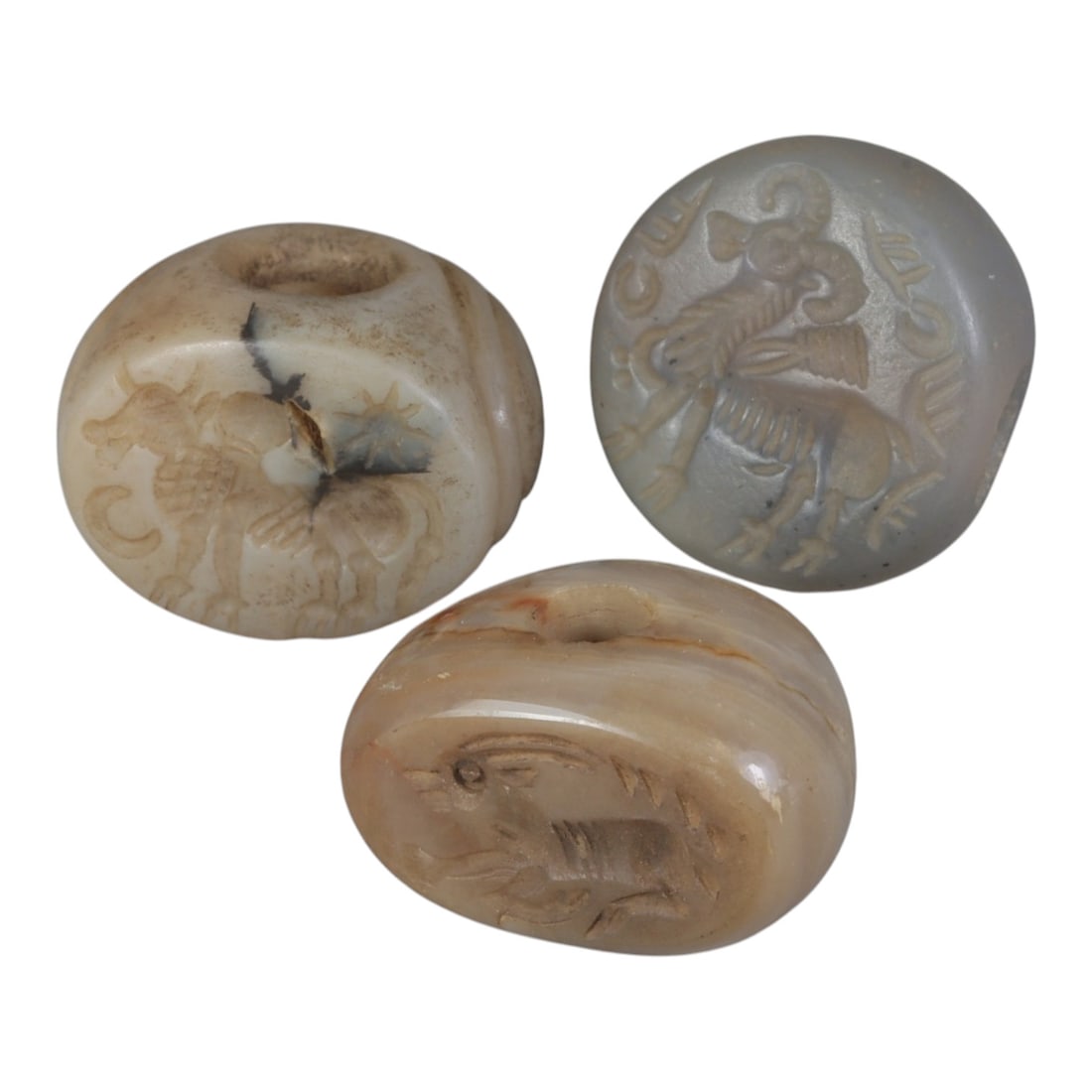Lot of 3 Ancient Sasanian Stone Stamp Seals, Circa 3rd-7th Century CE, 65WP: A collection of three Sasanian period stamp seals, carved from agate and banded stone, each featuring a central drilled hole for suspension. The seals display characteristic Sasanian iconography: incl