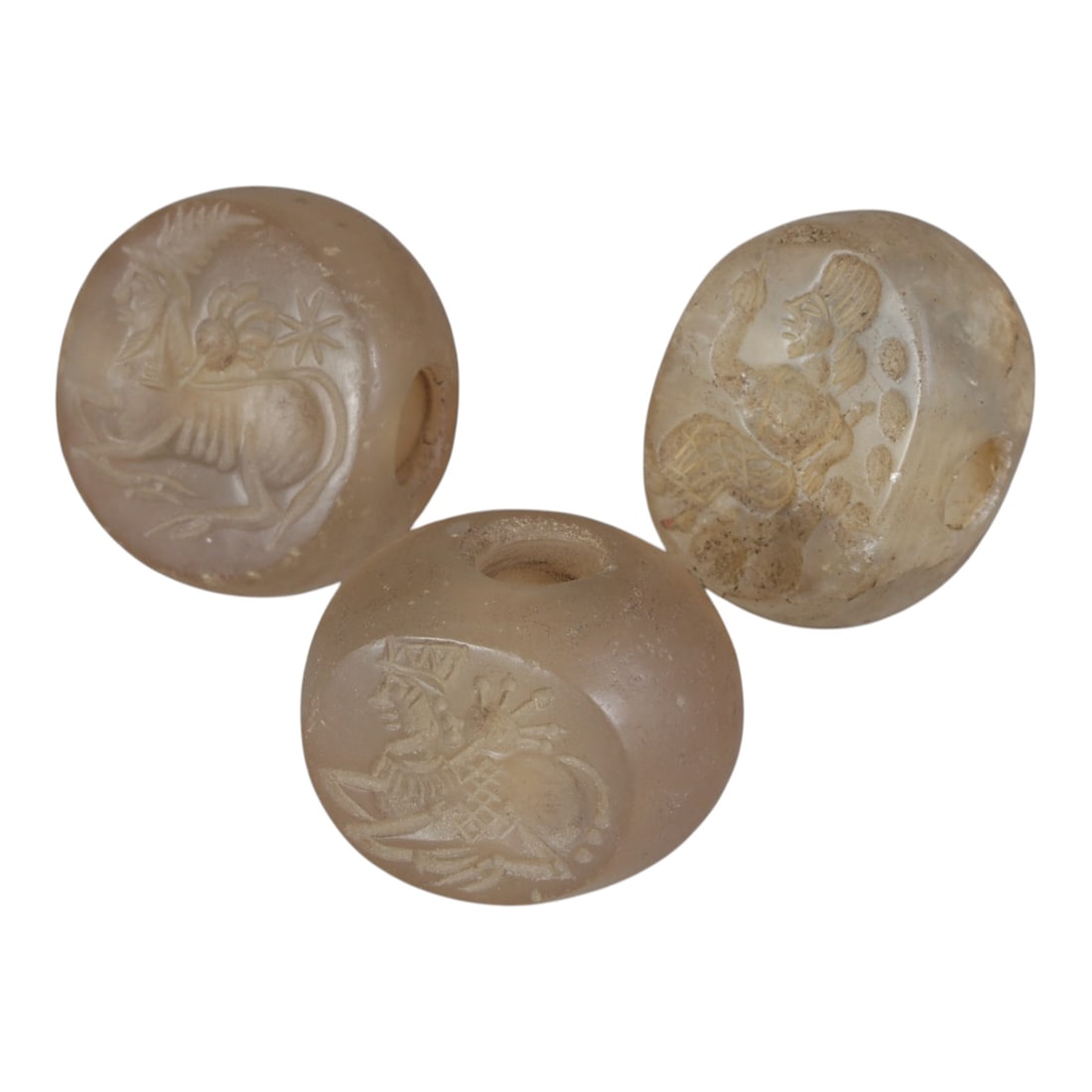 Lot of 3 Ancient Sasanian Chalcedony Stamp Seals, Circa 3rd-7th Century CE, 70WP: A collection of three Sasanian period stamp seals, expertly carved from translucent chalcedony stone, each featuring a central drilled hole for suspension. The seals display characteristic Sasanian ic