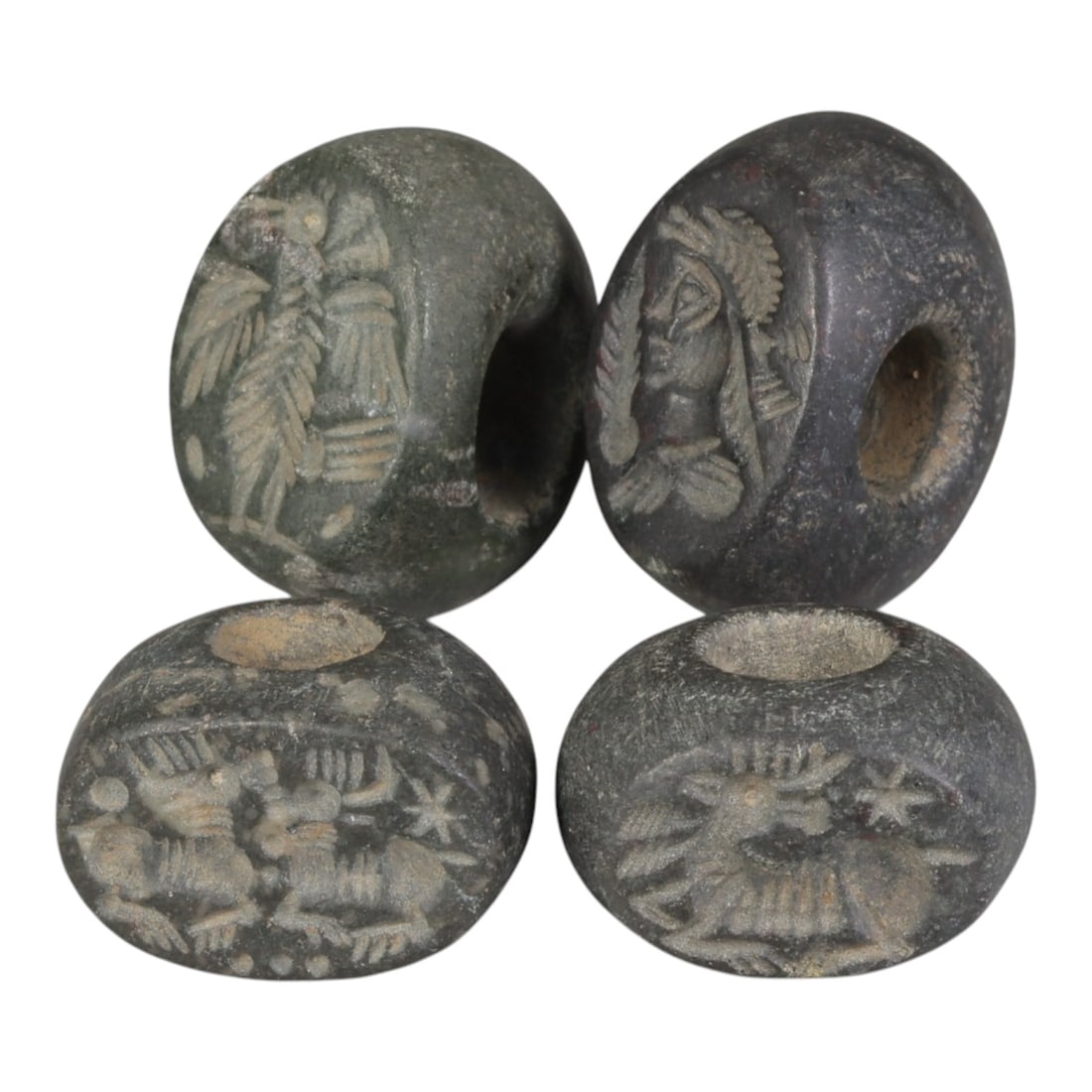 Lot of 4 Ancient Sasanian Stone Stamp Seals, Circa 3rd-7th Century CE, 72WP: A collection of four Sasanian period stamp seals, carved from dark grey/black stone, each featuring a central drilled hole for suspension. The seals display characteristic Sasanian iconography: includ