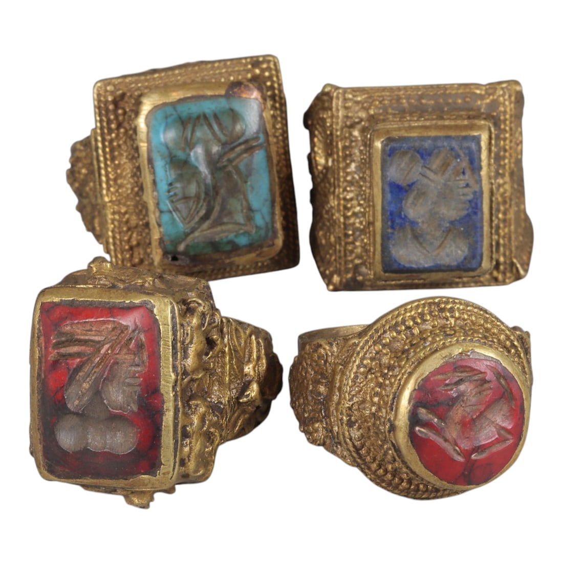 Lot of 4 Antique Qajar Period Gilt Intaglio Signet Rings, 63WP: A collection of four antique signet rings from the Qajar period, each set in ornate gilt metal with detailed granulation and embossed motifs. The rings feature varied gemstone intaglios: one with turq