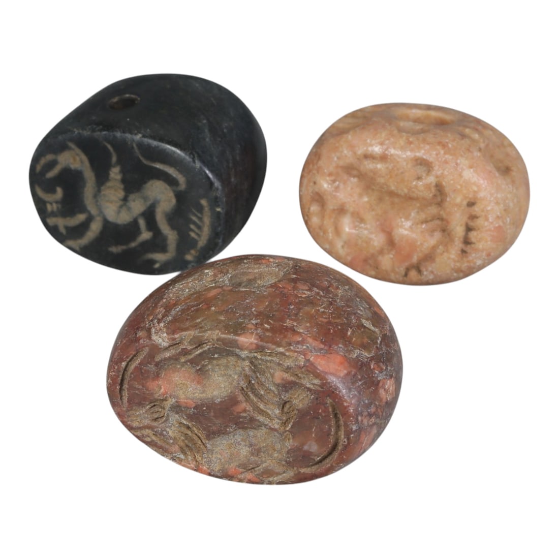 Lot of 3 Ancient Sasanian Stone Stamp Seals, Circa 3rd-7th Century CE, 68WP: A collection of three Sasanian period stamp seals, carved from varied stone types including dark grey, light pinkish, and reddish mottled stone, each featuring a central drilled hole for suspension. T